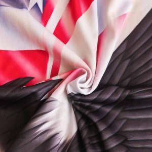 A vibrant car seat cover featuring a mix of red, white, and black, with intricate wing designs and a flag pattern.