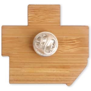A custom-shaped bamboo lapel pin in a light brown colour, featuring a logo on the back.