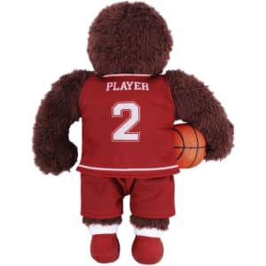 A brown plush toy dressed in a red basketball uniform, holding a miniature basketball, with a logo on the outfit.