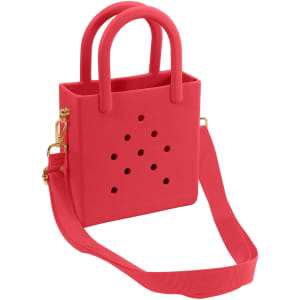 A mini beach bag in bright pink with cut-out holes and dual handles, featuring an adjustable shoulder strap.
