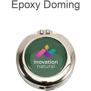 A round silver compact mirror with a green epoxy domed lid featuring a multicoloured logo and branding.