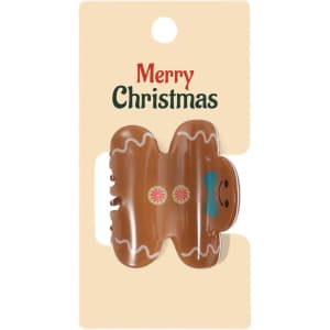 A Christmas-themed hair claw in the shape of a gingerbread man, featuring brown, pink, and blue colours on a card.