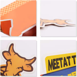 A close-up view of colourful promotional stickers featuring a cow design and text elements in orange and yellow.