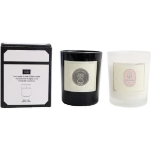 A black and white glass candle set displayed with a box, featuring a logo on each candle and a label with design information.