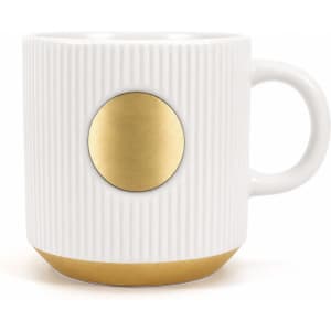 A ceramic coffee mug in white with ribbed texture and a bronze medal accent at the front.
