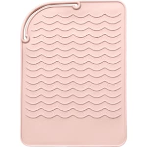 A pink silicone hair straightener pad with a textured wave design for heat protection and stability.