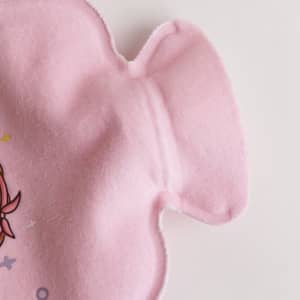 A pink hot water bottle with a plush cover featuring a soft texture and cartoon design.
