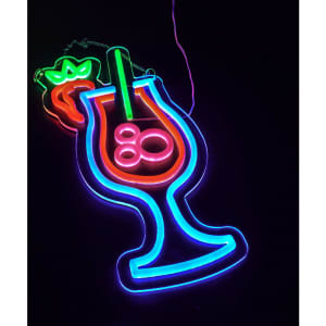 A neon LED sign featuring a colourful cocktail glass with a strawberry, glowing in green, blue, and pink.