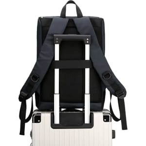 A navy blue business laptop backpack with adjustable straps resting on a silver suitcase.
