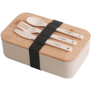 A lunch box in cream colour with a bamboo cover, secured by a black strap, accompanied by cutlery.