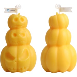 Triple pumpkin-shaped candles in yellow, featuring playful skull designs. Two stacked pumpkins visible.