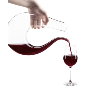 A U-shaped glass wine decanter in clear glass, pouring red wine into a wine glass.