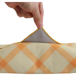A hand holding the edge of a yellow and orange checkered lunch box bag, revealing a grey lining inside.