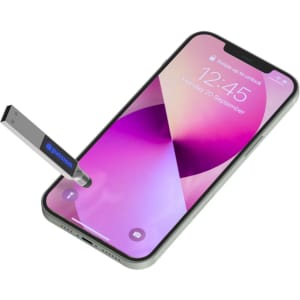A silver stylus and backlit logo flash drive next to a smartphone displaying a vibrant screen.