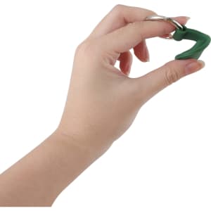 A green Air Tag protective case with a keyring, held by a hand against a white background.