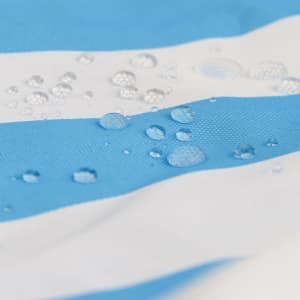A close-up of a blue and white striped fabric with water droplets on its surface, featuring a logo.