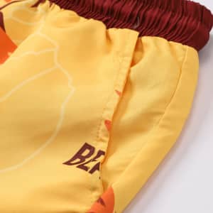 Men's polyester board shorts in yellow with a maroon waistband, featuring a vibrant tropical pattern and a logo.