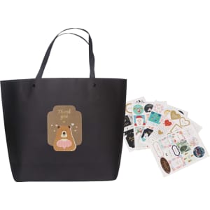 A medium black boutique paper bag with a bear illustration and multiple decorative stickers beside it.