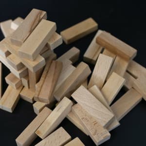 A stack of wooden blocks in various shades of light brown, scattered on a black surface.