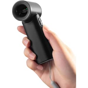 A black handheld fan is being held in a hand, featuring a sleek design and a small button.