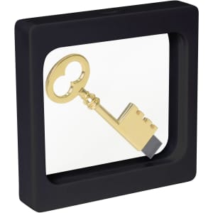 A gold key displayed inside a square black floating box with a clear front. The box includes a logo on the side.