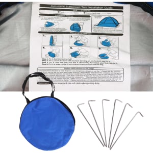 A blue pop-up beach tent with a carrying bag and six metal stakes for securing the tent.