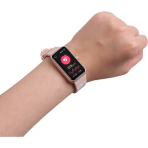 A pink square smart band worn on a wrist, displaying health metrics on its screen. The device has a logo.