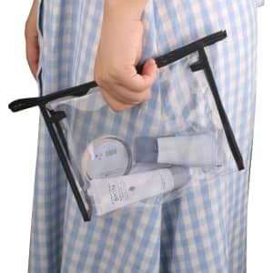 A clear PVC cosmetic bag with black trim, holding various toiletries and skincare products.