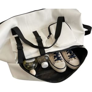 A white travel weekender bag with black straps, featuring sneakers and drink bottles inside. It has a pocket on the side.