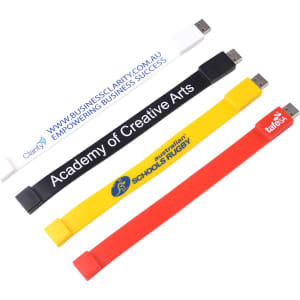 A set of four rectangular silicone wristband flash drives in white, black, yellow, and red, each with a logo.