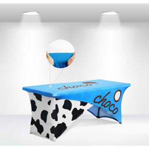 A blue and white stretch table cloth with a cow print design, featuring a branding logo on the top.