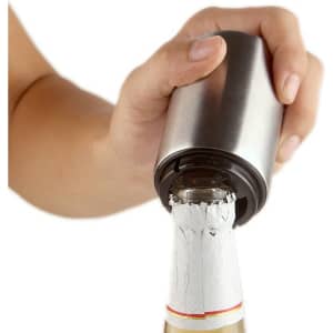 A drink bottle opener in stainless steel, being used to open a bottle with a white label.