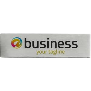 A metal name badge featuring a silver finish with a logo and text.