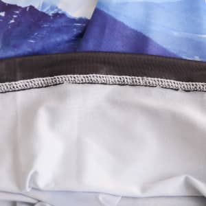 An Ice Silk Neck Gaiter featuring a mountain print in shades of blue and grey, with a smooth, elastic edge.