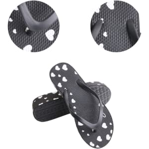 A pair of black thongs with white heart patterns, featuring a textured sole and curved straps.