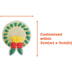 A circular shoe charm in yellow, green, and red, featuring a floral design, with a logo.