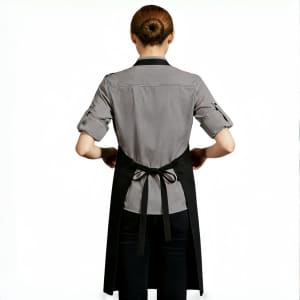 A person wearing a grey shirt and a black poly-cotton canvas full bib apron with neck strap, tied at the back.