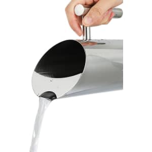 A stainless steel pitcher pouring water, featuring a sleek design and shiny finish, with a handle for easy gripping.