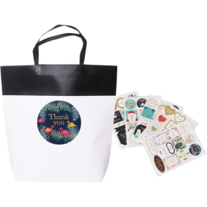 A large black and white boutique paper bag with a black handle, accompanied by assorted decorative stickers.