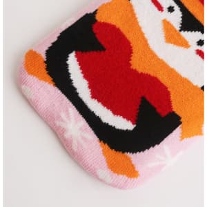 A hot water bottle with a knitted penguin cover in pink, red, black, and white hues, featuring a playful design.