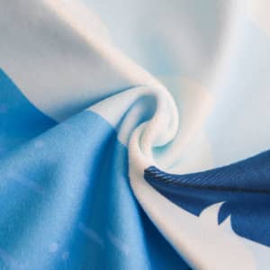 A microfibre beach towel in shades of blue, featuring a soft texture and vibrant patterns. It has a logo.