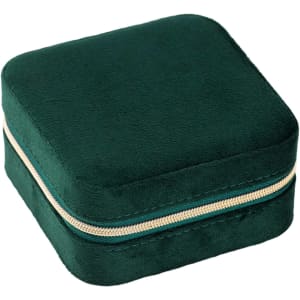 A square, deep green velvet jewellery organiser with a gold zipper. It has a soft texture and compact design.