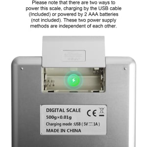 A rechargeable kitchen scale in silver with a green indicator light, featuring a USB charging port and battery compartment.