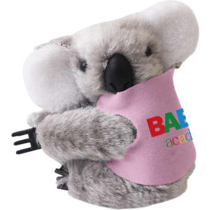 A grey koala plush toy with large ears, holding a black clip, featuring a colourful logo on its pink shirt.