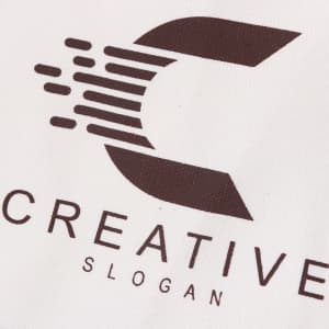 A large white canvas tote bag featuring a brown logo and text.