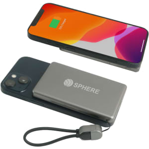 A grey 5000mAh aluminum magnetic power bank is positioned next to a smartphone displaying a battery charge indicator.