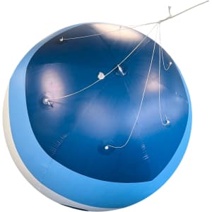 An inflatable advertising balloon in blue and white, featuring several attachment points and rigging lines.
