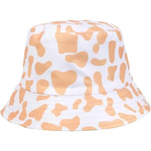 A cow print bucket hat featuring a white base with orange splashes and a circular brim. It has a logo on the side.