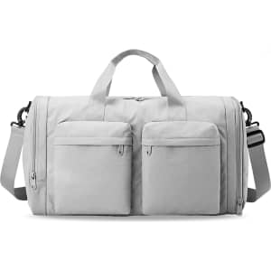 A foldable travel duffle bag in light grey with two front zippered pockets and a detachable shoulder strap.