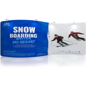 A blue S-shaped tension fabric display wall features skiing imagery, showcasing a ski resort promotion and a logo.